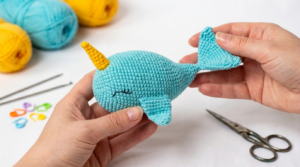 Baleia Unicórnio em amigurumi azul com chifre colorido feita em crochê para decoração lúdica ou presente infantil encantador.
