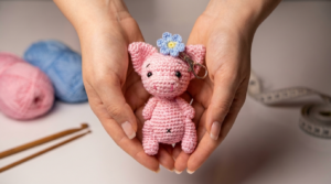chaveiro porquinho amigurumi receita gratis passo a passo, pequeno boneco de crochê rosa com enchimento macio e argola de metal para pendurar no contexto de um presente artesanal.