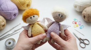Muñeca Eros amigurumi, muñeca de ganchillo en color beige y tonos vibrantes con alitas blancas para decoración infantil o regalo.