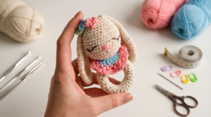 Sonajero de conejo amigurumi, pieza de ganchillo en color beige con detalles en rosa, ideal como juguete sensorial seguro para bebés.