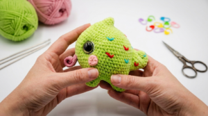 pequeno camaleão amigurumi em tons de verde e rosa feito com fio aveludado para decoração de quarto infantil criativa