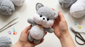 Cachorro Shiba Amigurumi cinza e branco feito em crochê fofo, posicionado como peça decorativa em um quarto infantil adorável.