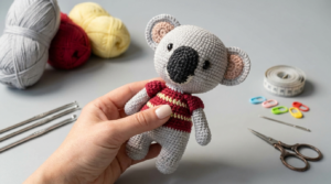 Coala Kevin amigurumi feito em crochê cor cinza com detalhes em rosa, projeto artesanal para decoração de bichinhos.