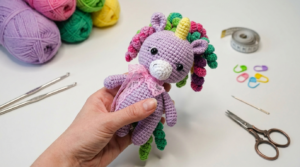 Unicórnio de crochê amigurumi feito com fio de algodão colorido e detalhes em brilho para decoração mágica de quartos.