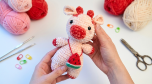 vaca melancia amigurumi receita gratis passo a passo, boneco de crochê rosa e verde com textura firme e detalhes em preto no focinho.