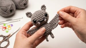 Murciélago llavero amigurumi tejido en hilo gris oscuro con ojos de seguridad, ideal para regalo artesanal.