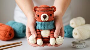 Tigre con bufanda amigurumi feito com fio de algodão vermelho e detalhes pretos, ideal para decoração infantil criativa.